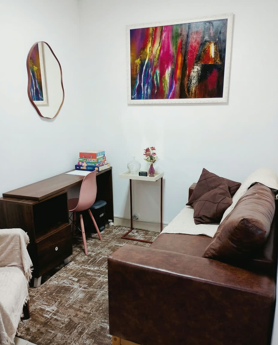 Ambiente com sofá marrom, mesa de atendimento e quadro colorido